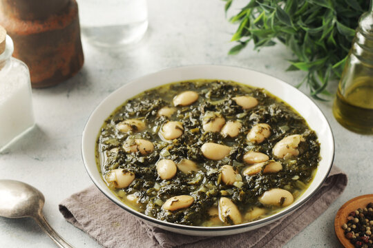 A bowl with traditional Tuscan kale salad and white beans soup Cavolo nero e fagioli
