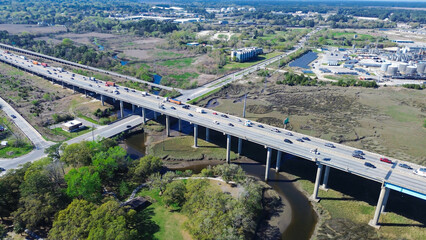 Fototapeta premium Elevated roadway spans expansive marshlands bordering major industrial zones river channels. Busy traffic flow connects regional freight hubs across maritime vistas within North Charleston, SC