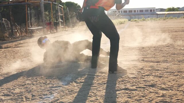 Young baseball player executing a safe slide into base during a competitive game, raising a cloud of dust on the field in slow motion