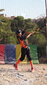 Slow motion footage of a kid swinging a baseball bat and running to first base during training. Youth league game on a sunny summer day