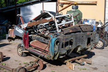 Fototapeta premium Pile of rusty classic car body panels and metal parts awaiting restoration in automotive salvage yard