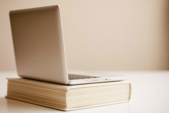 Laptop book balance minimal study concept education metaphor thin device hardcover book beige background clean surface copy space office object technology