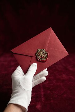 Elegant Red Envelope in White Gloved Hand on Luxury Red Background