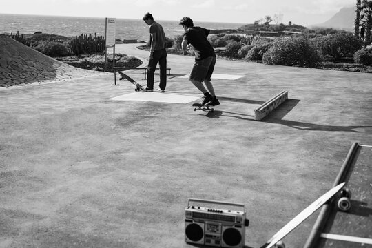 Young people having fun at skateboard park outdoor - Summer lifestyle and extreme sport concept - Main focus on right man body - Black and white film camera editing