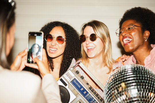 Group of multiracial girls having fun together dancing listening music while taking video reel with a smartphone outdoor - Party, nightlife and people lifestyle concept - Main focus on blond girl face