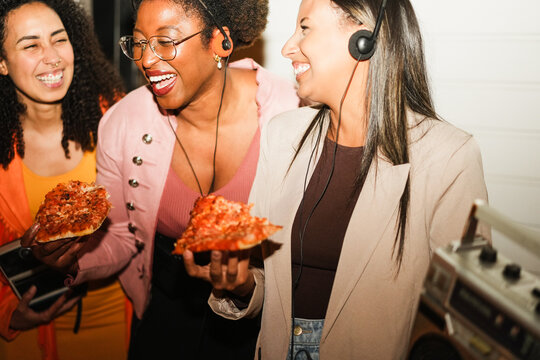 African american girls eating pizza outdoor in the streets after party concert - Food, people lifestyle and nightlife concept - Main focus on african woman face - UGC flash content