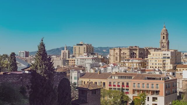 View of the roman theatre of Malaga, Spain on a sunny day. The Cathedral and Picasso Museum in the background.