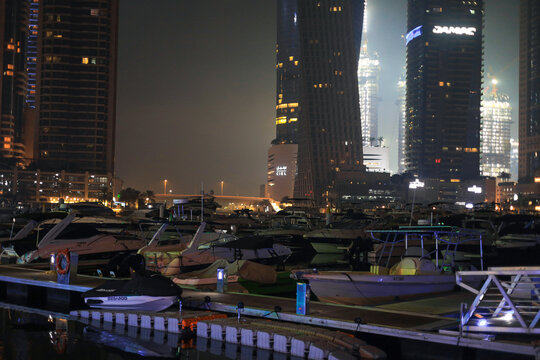 Dubai, UAE - June 16, 2026: Nighttime View Of Marina Filled With Moored Boats And Yachts With Tall Illuminated Skyscrapers