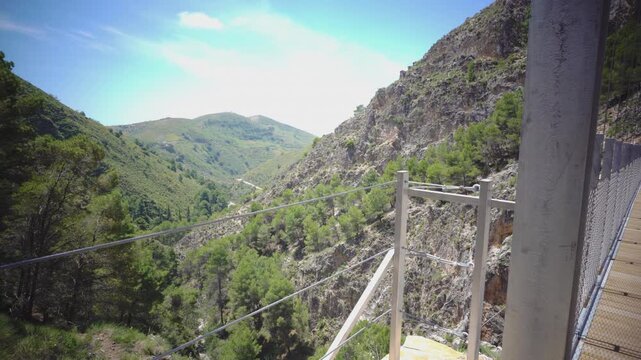 Suspension bridge of 'El Saltillo Canillas de Aceituno' in the beautiful mountain landscape of Canillas de Aceituno on a sunny day, Malaga, Spain