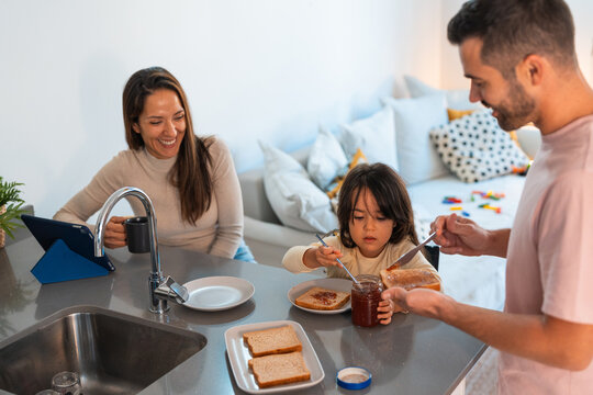 Family having breakfast together at home while the mother working