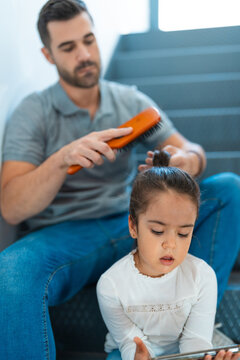 Father combing the hair of his daughter