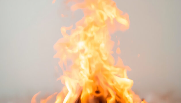 A close-up shot of vibrant orange and yellow flames rising against a smoky, light grey background