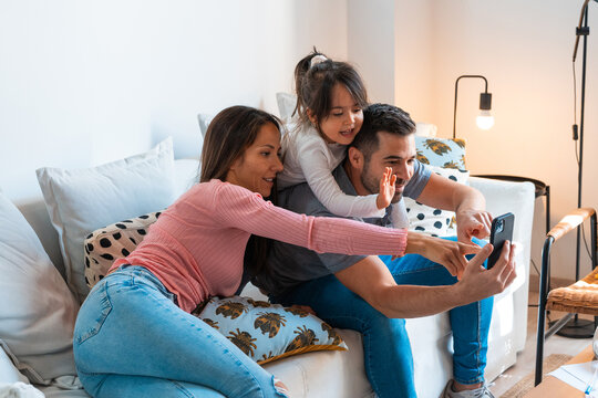 Family waving while taking a selfie together at home