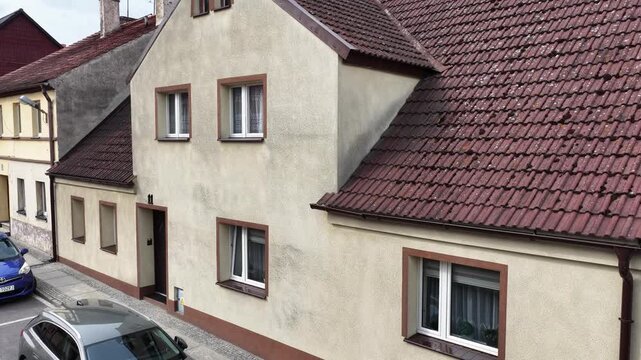 Small building with dirty roof tiles, moss, lichen and weathered facade before pressure washing, exterior cleaning and roof renovation.