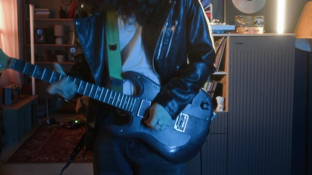 Young rocker energetically jumping and playing electric guitar in home studio. Clip for youth lifestyle brands, music education marketing, or creative hobby advertisements