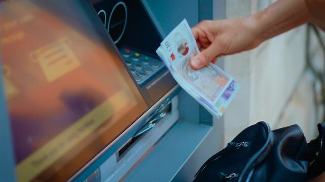Withdrawing cash from automated teller machine and counting banknotes after transaction. Woman holding wallet and paper money near outdoor ATM during personal banking operation. Financial services