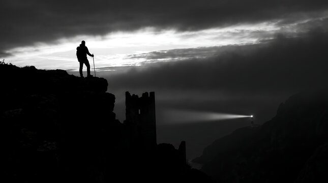 Silhouette of Hiker on Cliff Overlooking Castle Ruins and Lighthouse at Night