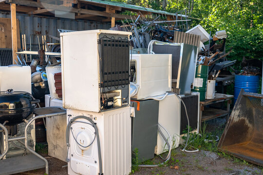 Discarded household appliances and electronic waste at outdoor recycling center awaiting processing