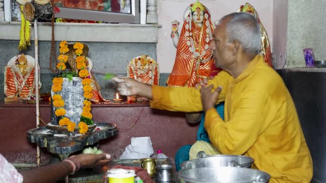 Elderly couple Hindu Couple Performing Shiva Lingam Abhishek During Traditional Temple Worship