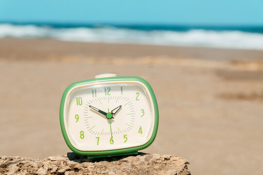 a close-up of a green clock at a quiet beach