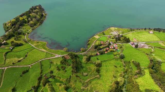 An aerial wide shot showcasing a slow drone reveal of the green volcanic crater lake Lagoa das Sete Cidades in image d02e77 jpg bordered by steep mountain ridges on Sao Miguel Island Azores Portugal