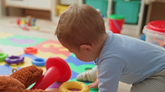 Boy with open mouth crying among scattered toys on colorful foam playmat inside building near storage bins and plastic container; distress frustration.