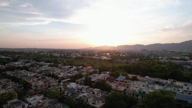 Golden sunset casts warm light across residential neighborhoods with Margalla Hills on the horizon, Islamabad, Pakistan