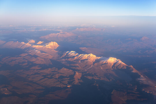 Sunrise Over Snow-Covered Mountain Peaks Seen from an Airplane