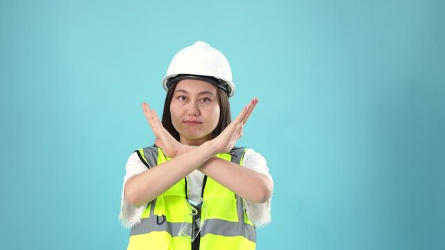Construction worker making an x gesture with hands, in blue background, with hard hat, high-visibility vest, with textile vest, plastic hat texture, from a frontal view perspective.