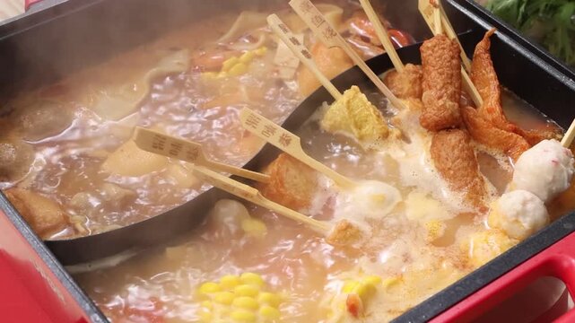 Close up of steaming hot pot and oden skewers boiling in broth
