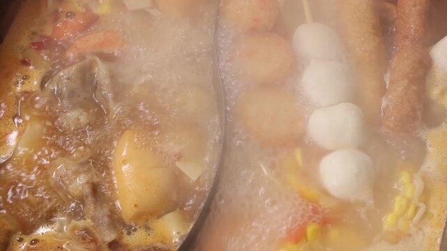 Slow motion close up of hot steaming oden boiling in a divided pot