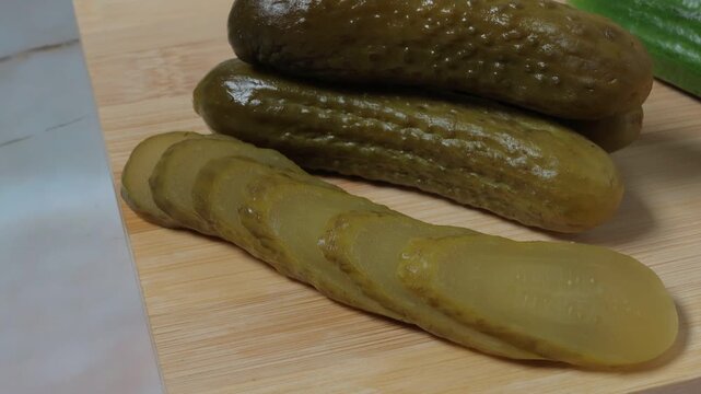 Sliced ​​pickled cucumbers on a wooden table, left side, zoom-out effect.