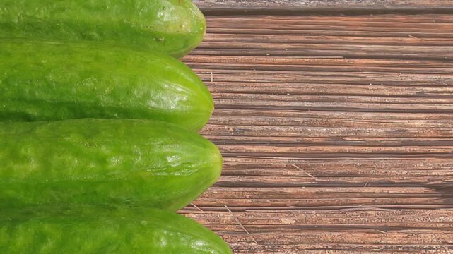 Cucumber on a wooden table, left side, zoom-out effect.