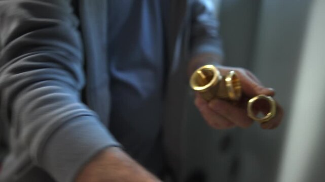 Plumber applying sealant to brass pipe fitting