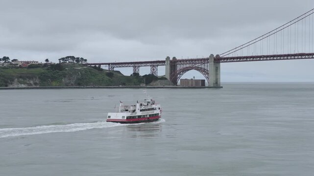 Passenger Ferry Crossing San Francisco Bay Under Golden Gate Bridge With Misty, Overcast Sky - Circling Aerial Shot