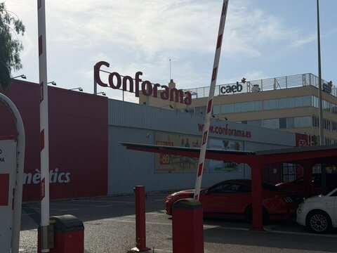 Mallorca, spain, june 27, 2026, conforama furniture store exterior facade and parking area with entry barrier and customer vehicles on sunny day