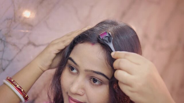 Young lady using derma roller on thinning scalp area in indoor setting, female pattern baldness.