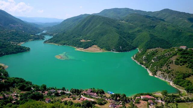 Castel di Tora Turano Lake Italy 4K Drone. Panning view left to right backward flight of rugged coastline hilltop borgo town. Borghi piu belli d Italia most beautiful villages scenic video