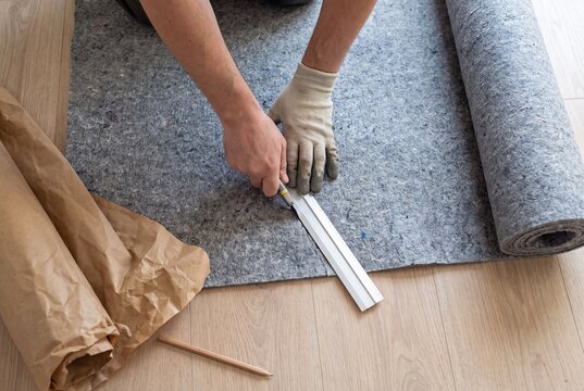 Worker cutting carpet underlay with utility knife