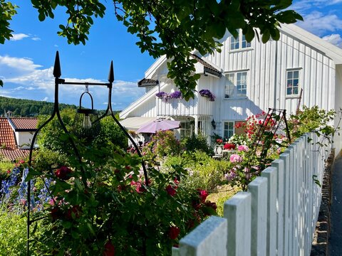 Son white wooden house with colorful cottage garden and picket fence