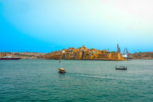 valletta skyline urban cityscape malta capital city view from grand harbour bay of water with boats in Mediterranean Sea with clear blue summer skies overhead on sunny day