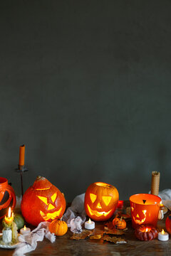 Happy Halloween. Carved halloween pumpkins with burning candles, spiders, bats on table against dark background. Atmospheric halloween decorations, holiday banner