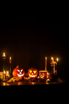 Happy Halloween. Carved glowing halloween pumpkins, burning candles and spooky spiders in dark. Atmospheric halloween night with jack o lantern decorations. Boo. holiday banner