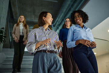 Diverse businesswomen walking and discussing in office building