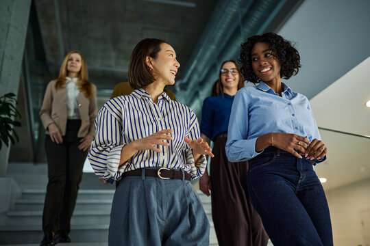 Diverse businesswomen walking and discussing in office building