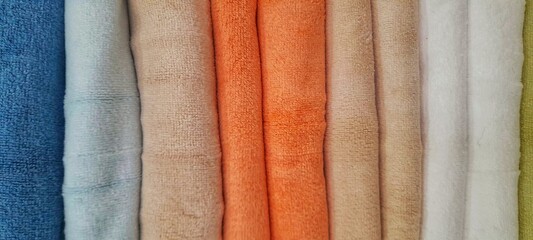 Colorful towels background A stack of rolled towels or blankets made from fine microfiber or fleece with a striped texture. The image can be used for backgrounds, wallpaper, designs, and more. © Abdurrahman Wayang 