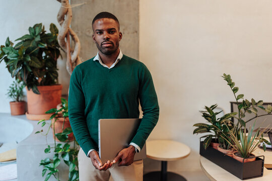 Black entrepreneur holding laptop standing in office