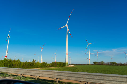 Large wind turbines standing against a clear blue sky on a sunny day, producing clean renewable electricity. Concept of sustainable energy, green technology, environmental protection