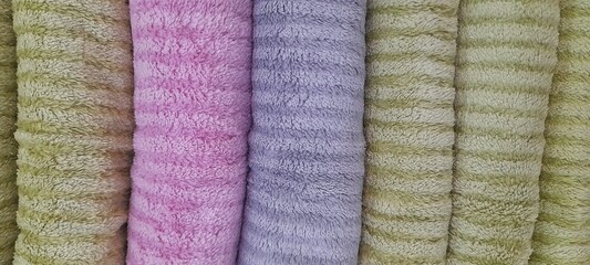 Colorful towels background A stack of rolled towels or blankets made from fine microfiber or fleece with a striped texture. The image can be used for backgrounds, wallpaper, designs, and more. © Abdurrahman Wayang 
