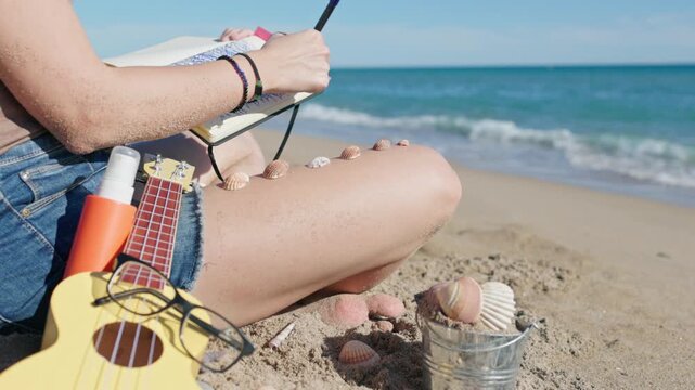 Creative woman drawing in a sketchbook and journaling on the beach